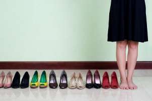 Woman standing next to several pairs of cute high heels